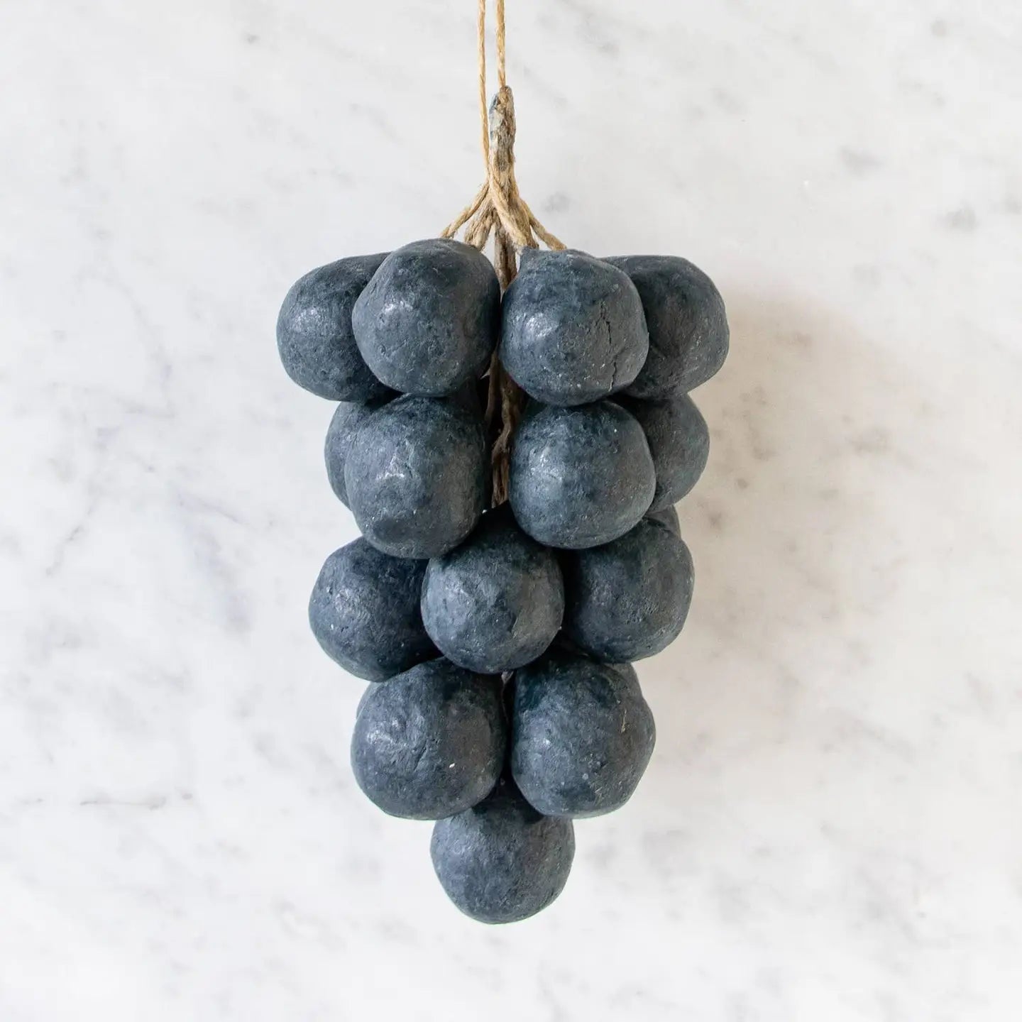 Slate grey handcrafted soap shaped like a grape cluster on a wooden surface