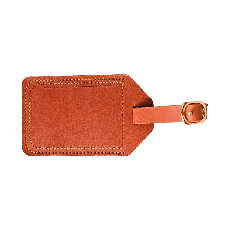 Genuine tan leather luggage tag with metal loop attachment on a suitcase