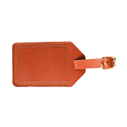 Genuine tan leather luggage tag with metal loop attachment on a suitcase