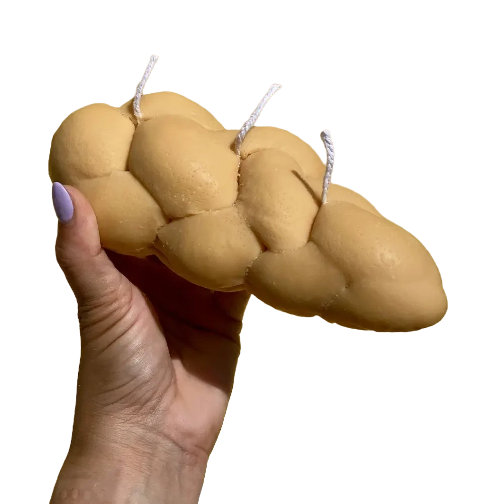 Realistic challah bread shaped candle with braided texture in golden brown tones