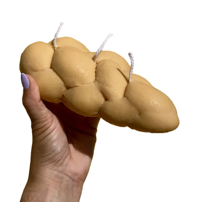 Realistic challah bread shaped candle with braided texture in golden brown tones