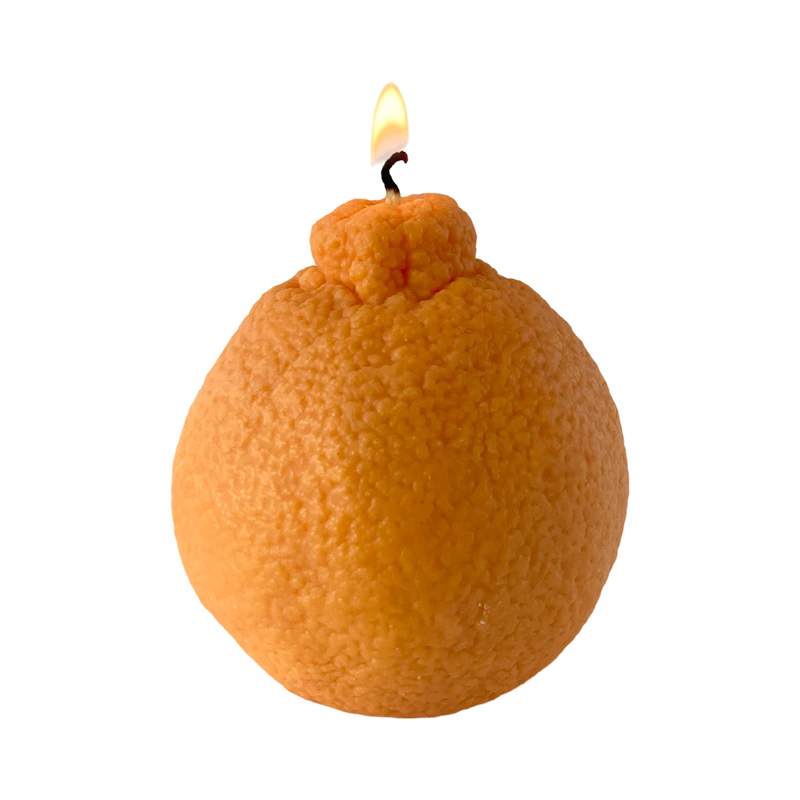 Realistic orange fruit shaped candle with green leaf detail on neutral background