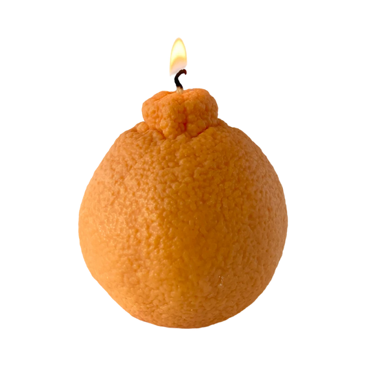 Realistic orange fruit shaped candle with green leaf detail on neutral background