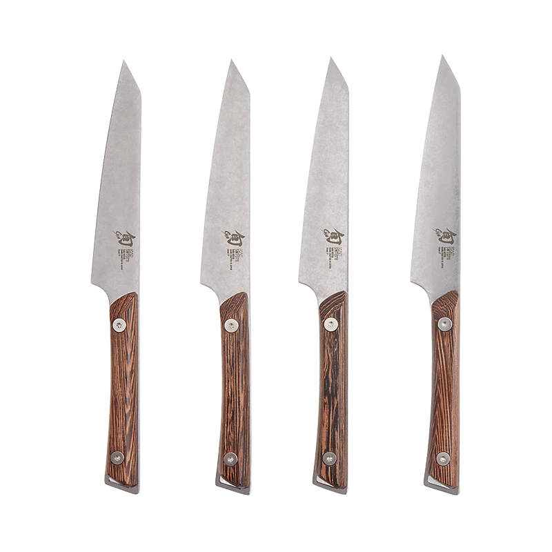Set of four Shun Kanso steak knives with wooden handles arranged on a surface