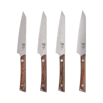 Set of four Shun Kanso steak knives with wooden handles arranged on a surface